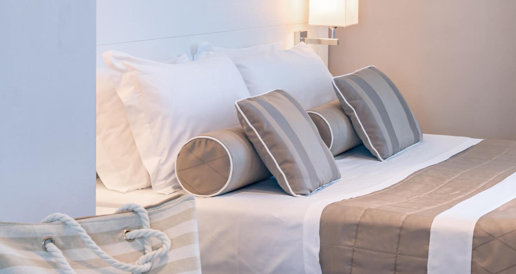 Modern bedroom with striped pillows and a bedside lamp.