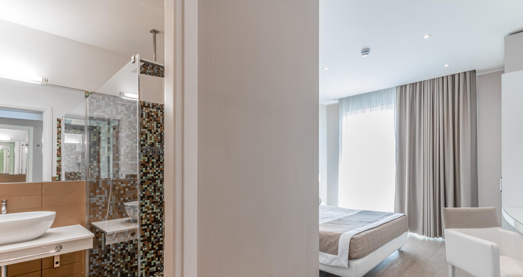 Modern bathroom with mosaic, elegant sink, and white towels.
