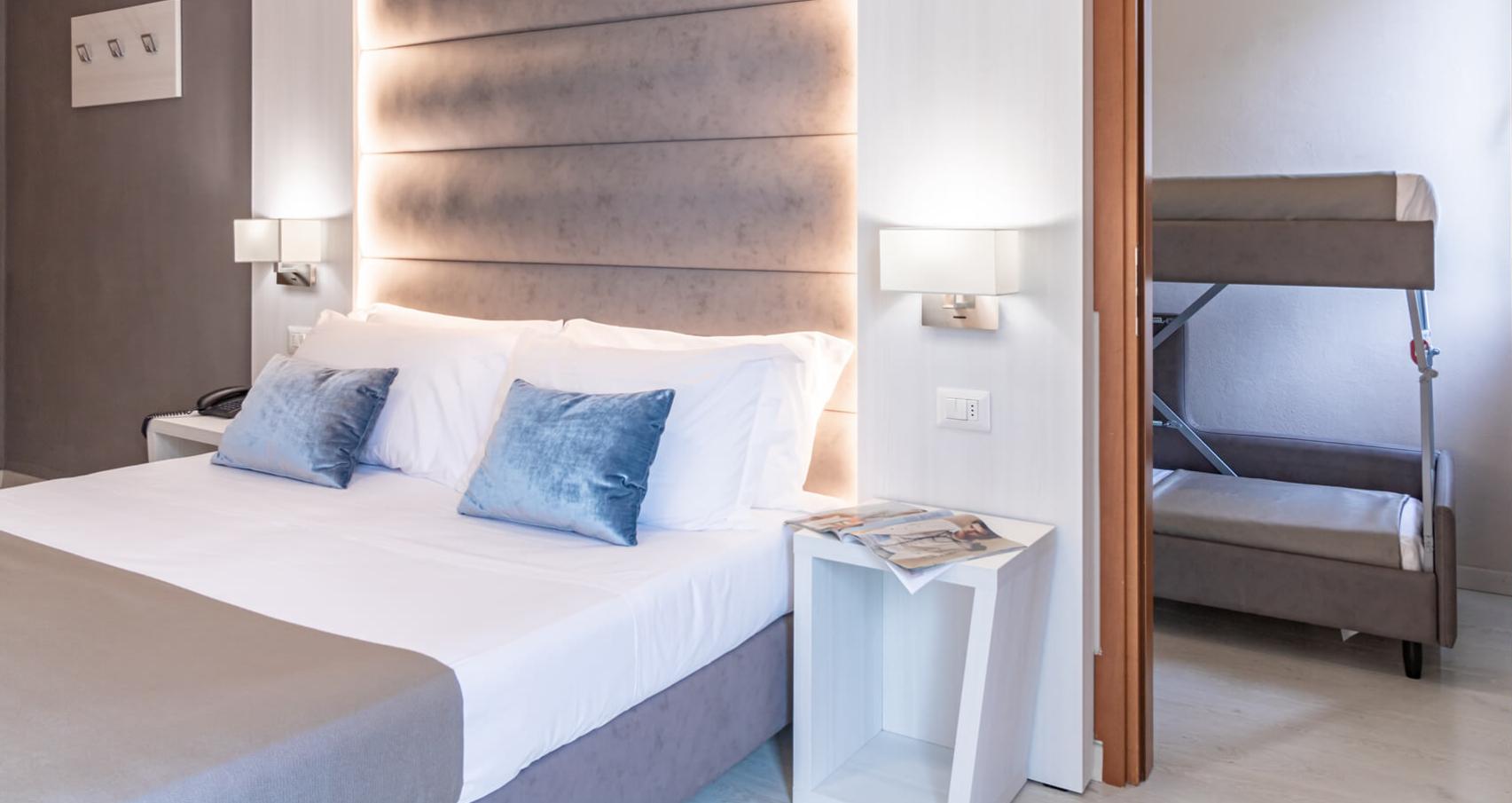 Modern bedroom with gray pillows and wall lamp.