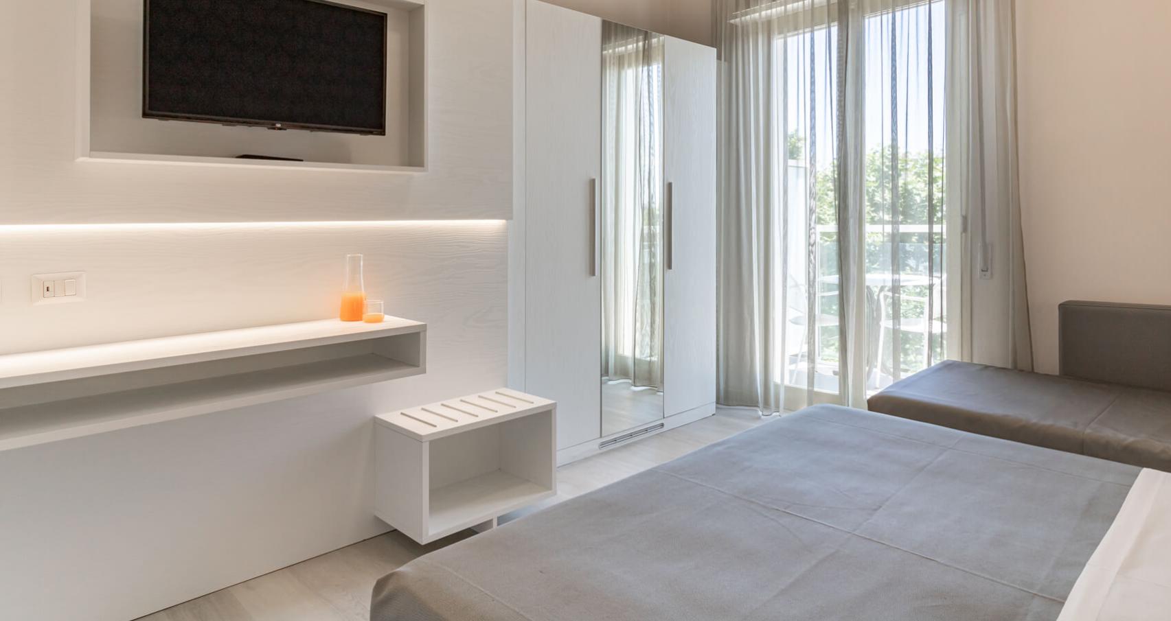 Bright room with TV, mirrored wardrobe, and balcony access.