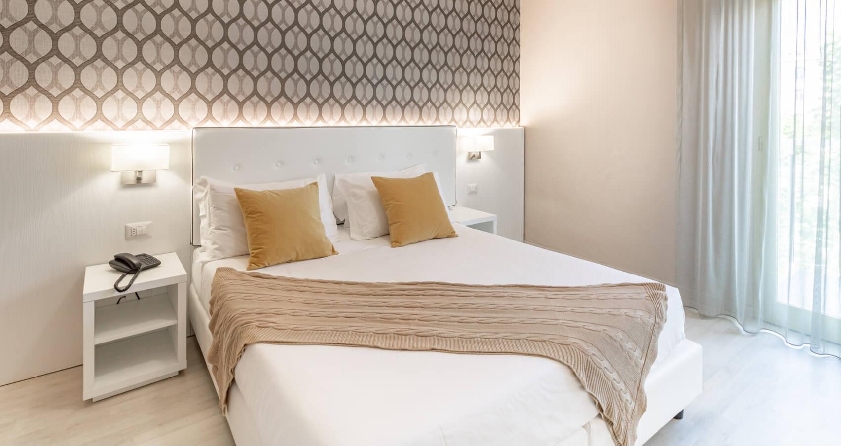 Modern room with a double bed, gray sheets, and white towels.