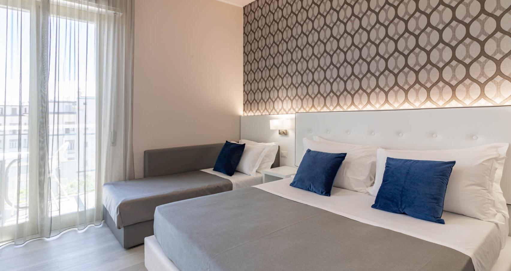 Modern room with double bed and sofa, decorated with blue pillows.