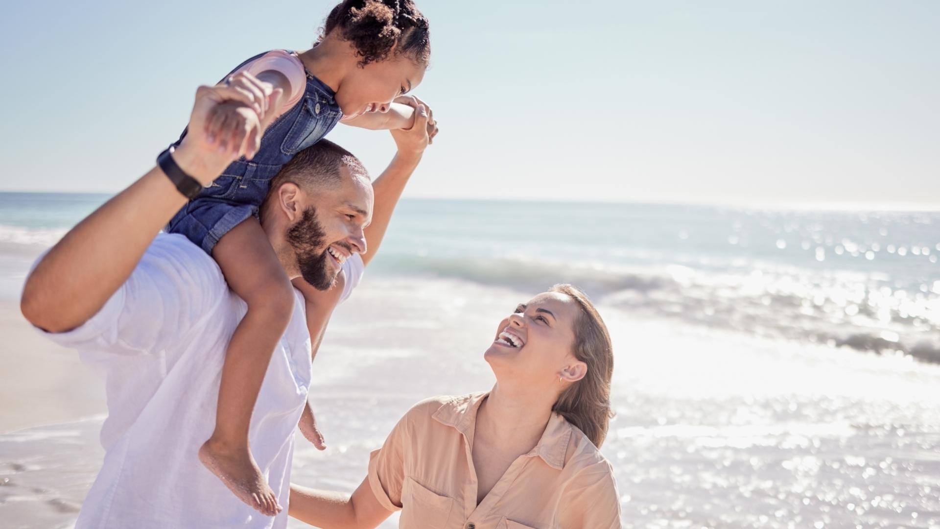 Famiglia felice si diverte in spiaggia con il mare sullo sfondo.