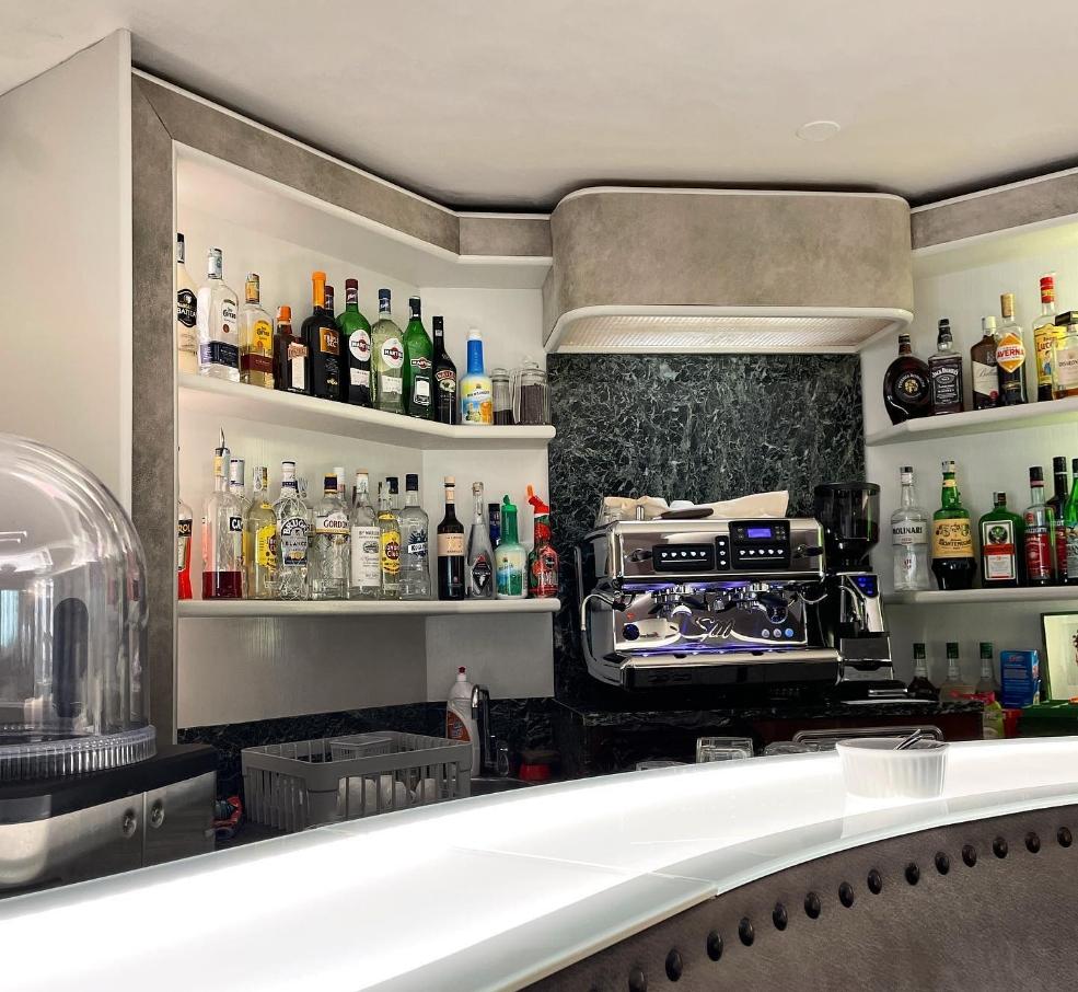 Bar con scaffali di liquori e macchina per caffè espresso.