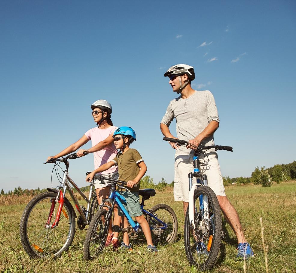 Famiglia in bicicletta all'aperto in una giornata di sole.