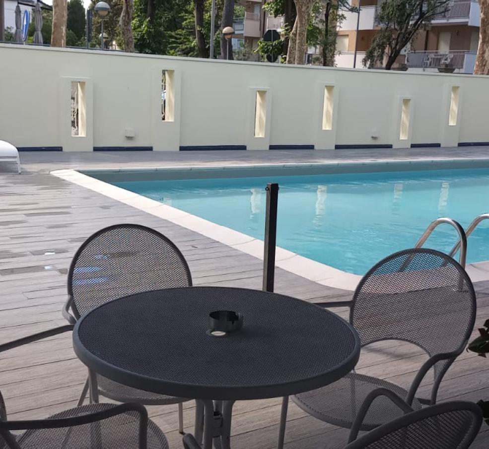 Piscina all'aperto con lettini e tavolini in un'area relax.