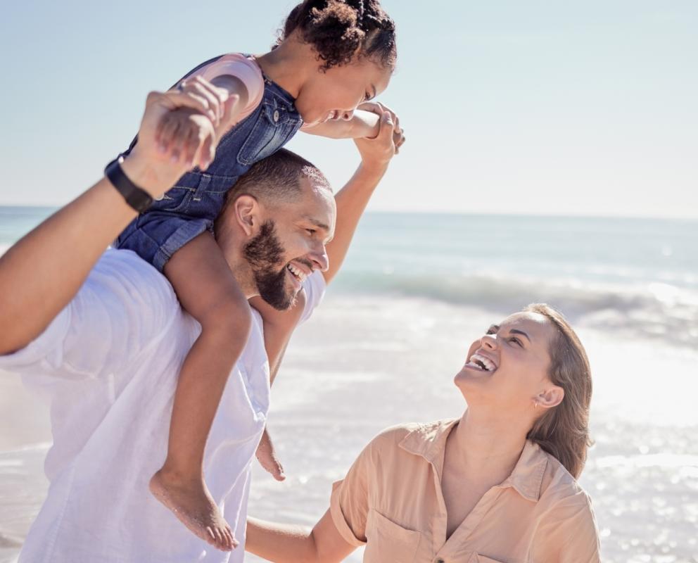 Famiglia felice si diverte in spiaggia con il mare sullo sfondo.